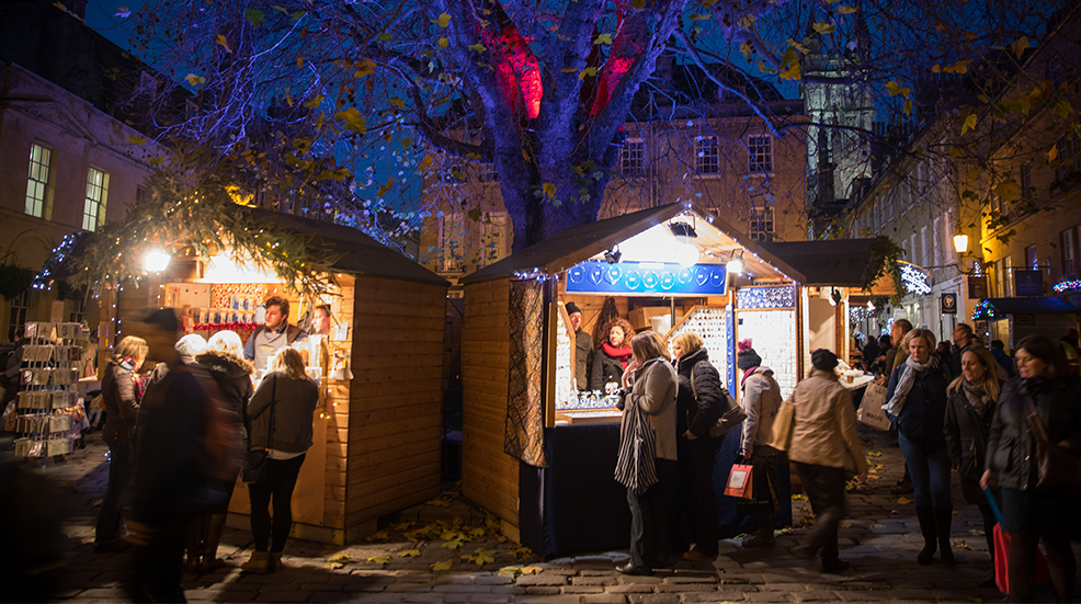 Christmas shoppers browse stalls at the traditional Christmas market that has opened close to the historic Roman Baths and Bath Abbey